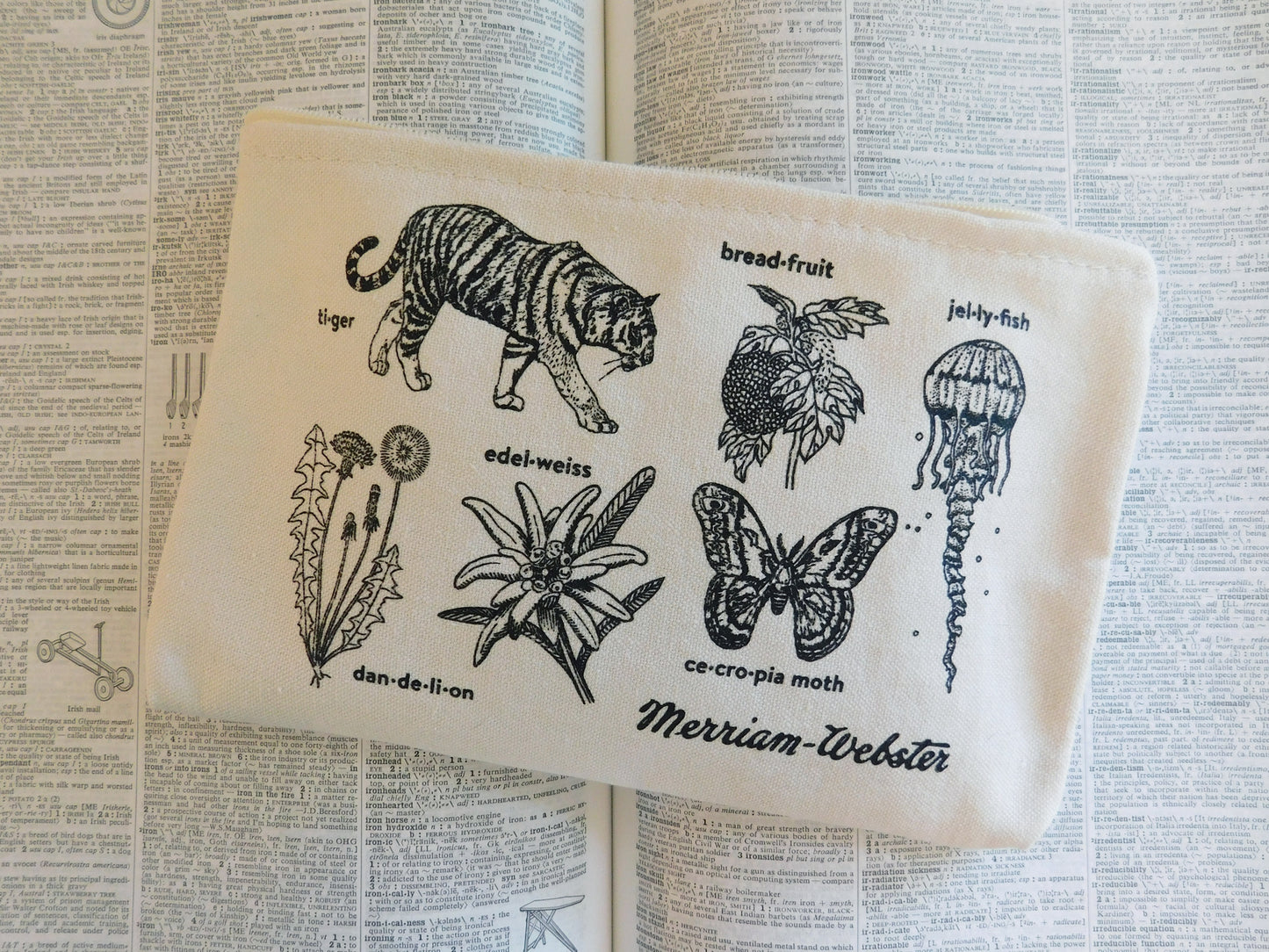 Image of a cotton zip pouch with hand-drawn illustrations of plants and animals paired with their headword, with the Merriam-Webster vintage logo in the lower right.