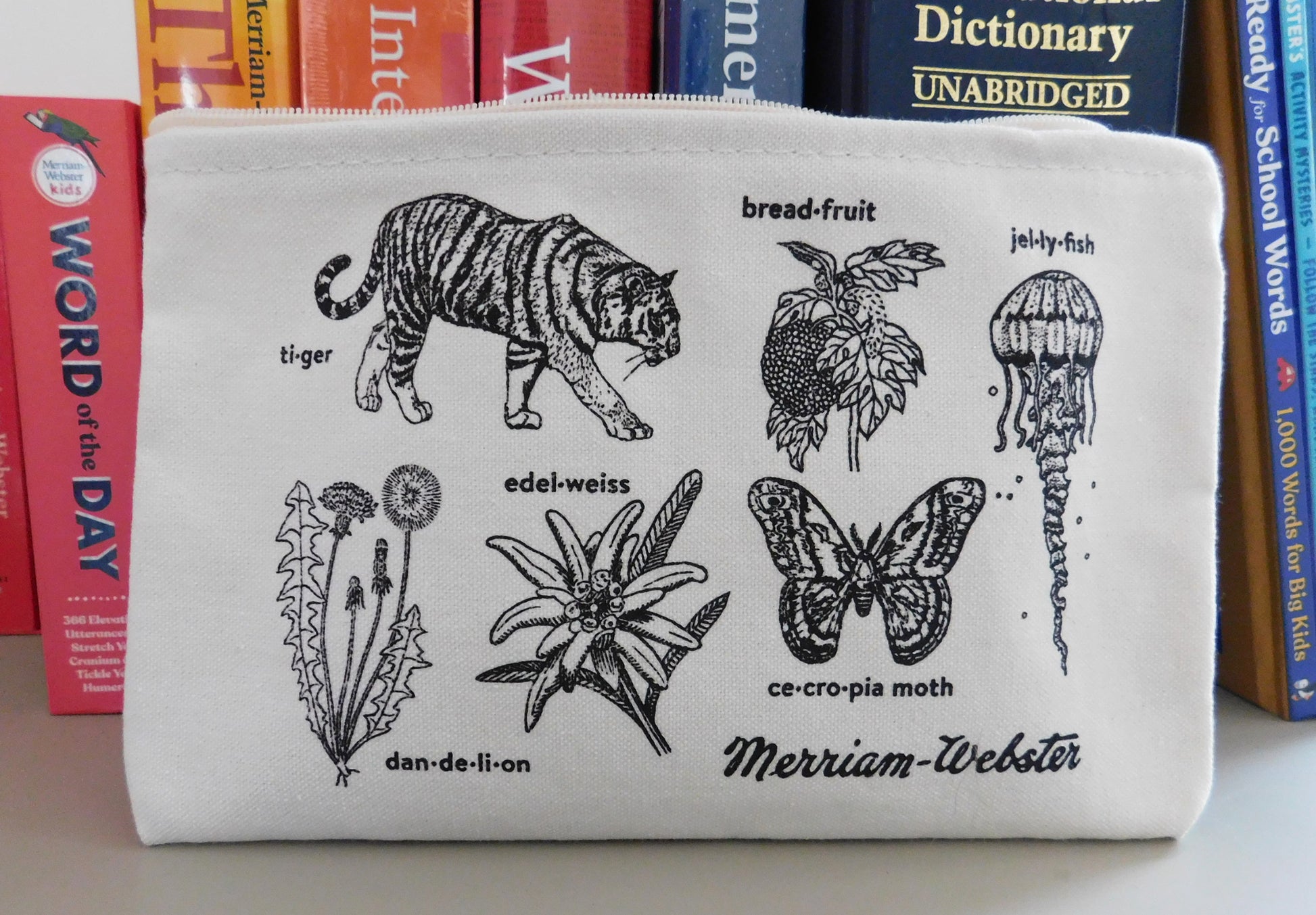 Image of a cotton zip pouch with hand-drawn illustrations of plants and animals paired with their headword, with the Merriam-Webster vintage logo in the lower right.